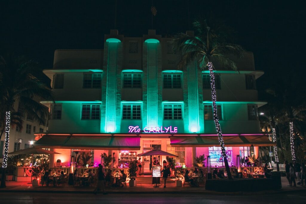 A neon-lit building has a bustling outdoor restaurant