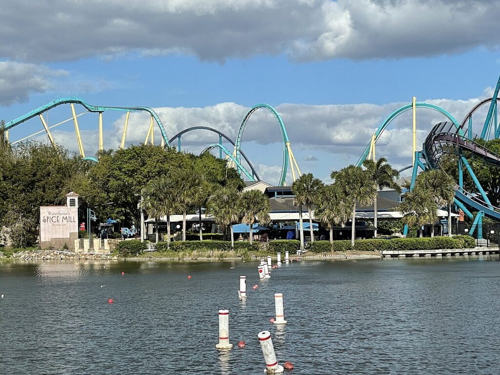 Kraken's loop and teal hills beyond the lake and the lakeside buildings, SeaWorld Orlando, March 2021 - ThrillZing.jpg